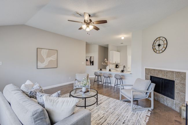 Living area with wood finished floors, ceiling fan, a fireplace, lofted ceiling, and baseboards | Image 17
