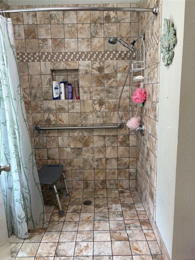 Bathroom featuring a tile shower and a textured wall | Image 8