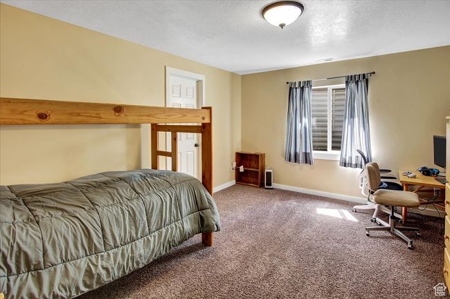 Bedroom with carpet floors, a textured ceiling, baseboards, and visible vents | Image 21