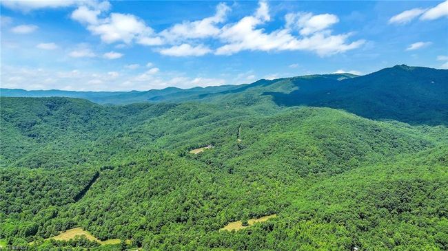 Immerse yourself in the serene beauty of the North Carolina mountains from the three-level rustic cabin's deck, where each sunset paints a breathtaking tableau of natural tranquility and rustic charm. | Image 10