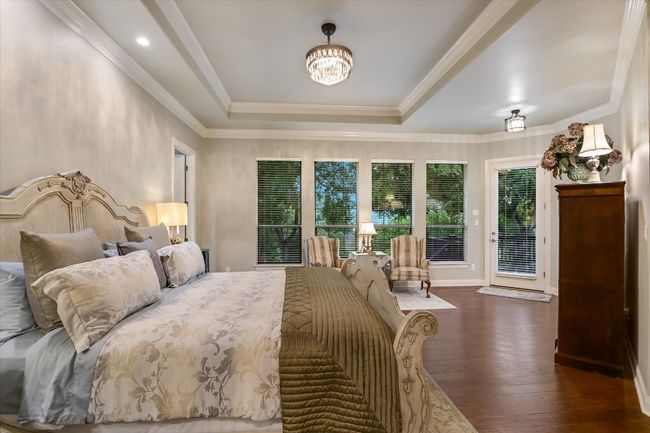 Primary Bedroom with access to exterior, wood finished floors, a tray ceiling, a chandelier offering various light settings to match desired ambience, and ornamental molding | Image 13