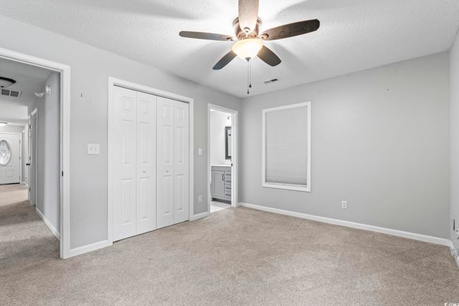Unfurnished bedroom with carpet flooring, a closet, a textured ceiling, connected bathroom, and ceiling fan | Image 22