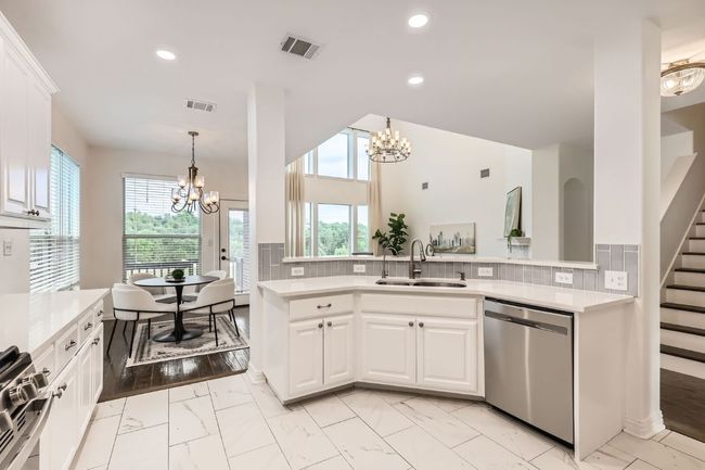 Kitchen featuring stainless steel appliances, a sink, a chandelier, light marble finish floors, and recessed lighting | Image 6