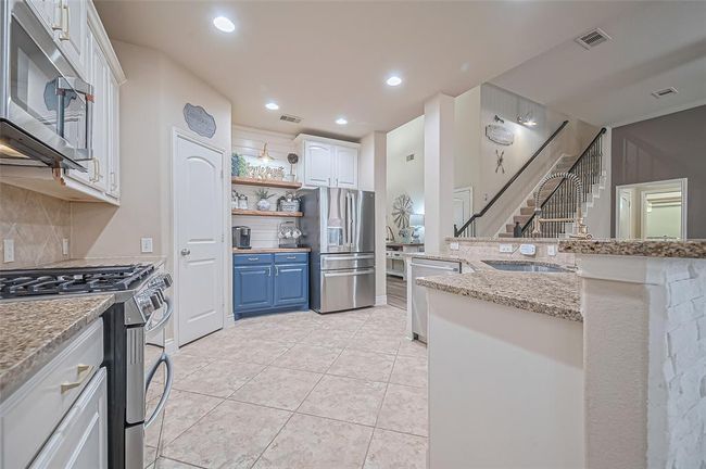 The wraparound cabinetry in this open-concept kitchen maximizes storage and workspace, making it perfect for preparing meals and entertaining guests. | Image 14