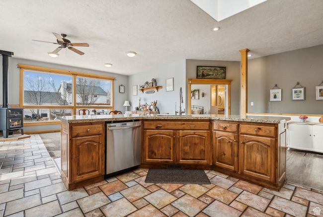 Kitchen with stainless steel dishwasher, a sink, ceiling fan, a wood stove, and stone finish floor | Image 13