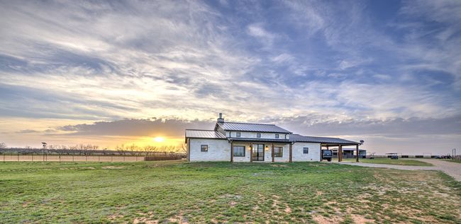 View of front facade featuring a yard, metal roof, a chimney, and fence | Image 5