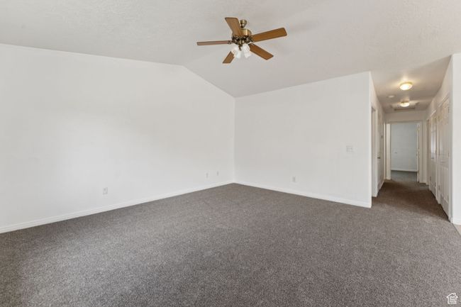 Spare room featuring dark carpet, vaulted ceiling, and ceiling fan | Image 18