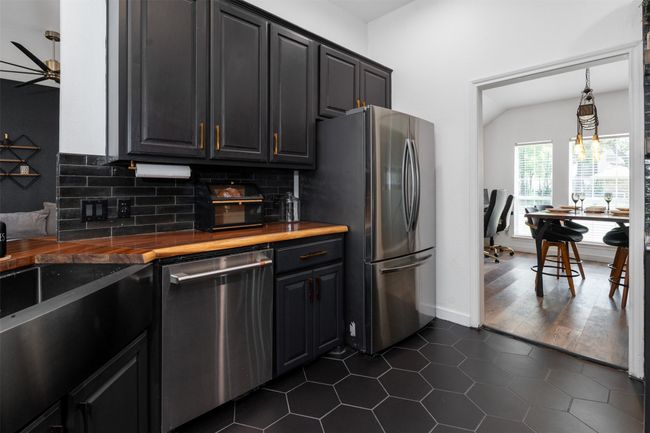 Kitchen with wood counters, dark tile patterned flooring, ceiling fan, stainless steel appliances, and backsplash | Image 4