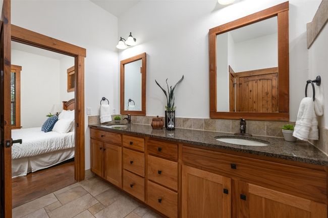 This expansive primary bath offers more than just dual sinks—it includes a spacious walk-in shower with both rainfall and handheld shower heads, a private water closet, and ample storage in both a linen closet and a walk-in closet. | Image 15