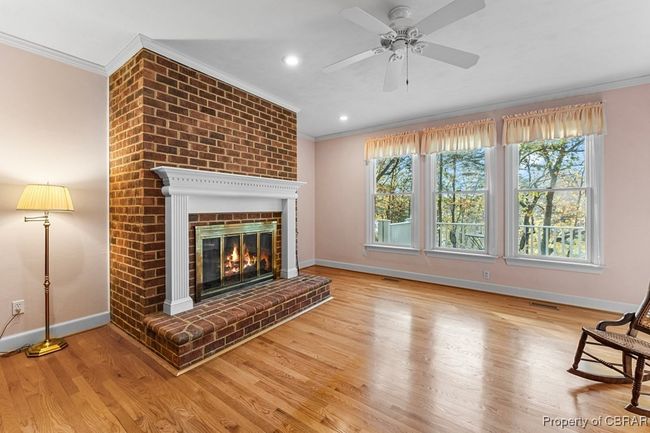 Unfurnished living room with ornamental molding, healthy amount of natural light, a brick fireplace, wood finished floors, and a ceiling fan | Image 18