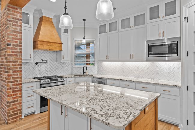 Kitchen featuring crown molding, stainless steel appliances, a kitchen island, white cabinets, and backsplash | Image 8