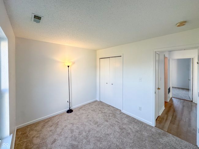unfurnished bedroom featuring carpet flooring, visible vents, a textured ceiling, and baseboards | Image 15