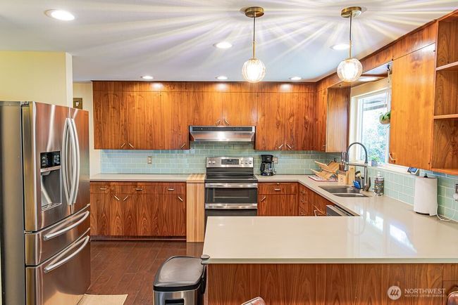 The kitchen features stainless steel appliances and quartz counters. | Image 6