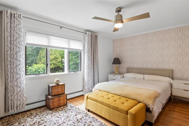 Bedroom with a baseboard radiator, wood finished floors, and a ceiling fan | Image 23