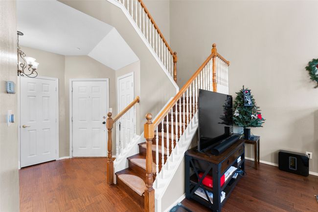 Stairs with baseboards, a towering ceiling, an inviting chandelier, and wood-type flooring | Image 5