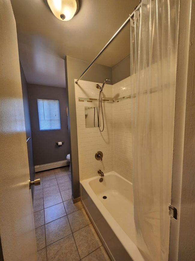 Full bathroom featuring shower / tub combo, tile patterned flooring, and baseboard heating | Image 7