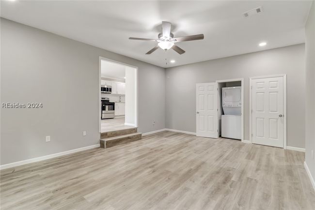 Unfurnished bedroom featuring stacked washer / drying machine, light wood-type flooring, and ceiling fan | Image 19