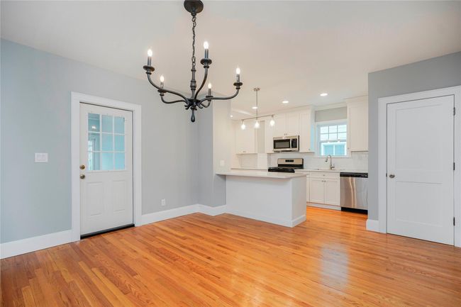 Kitchen with a chandelier, light wood finished floors, backsplash, and stainless steel appliances | Image 12