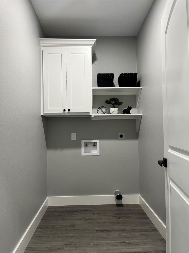 Laundry area with hookup for an electric dryer, dark wood-style flooring, washer hookup, and cabinet space | Image 21