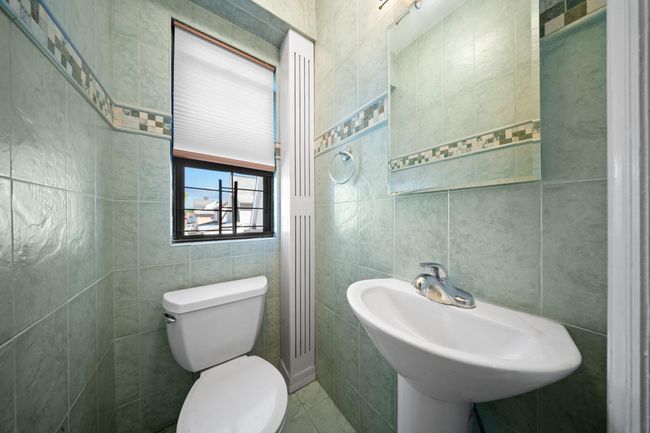 Half bathroom featuring tile walls, toilet, a sink, and tile patterned floors | Image 28