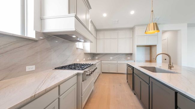 Kitchen featuring light stone counters, decorative backsplash, custom range hood, a sink, and appliances with stainless steel finishes | Image 12