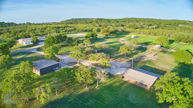 Aerial view of property featuring the home, 2 workshops, and stalls. The view is amazing!! | Image 35
