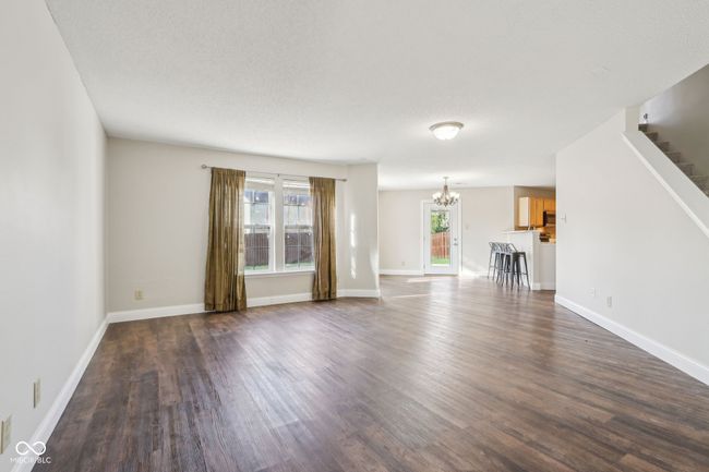 unfurnished living room featuring a chandelier, healthy amount of natural light, stairway, and dark wood finished floors | Image 19