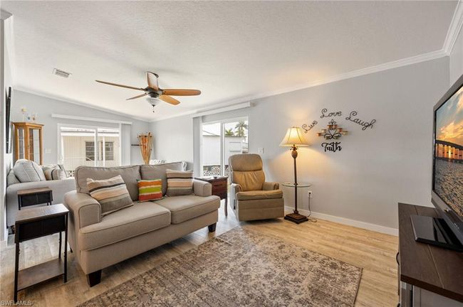 Living room featuring wood finished floors, a ceiling fan, ornamental molding, and baseboards | Image 14