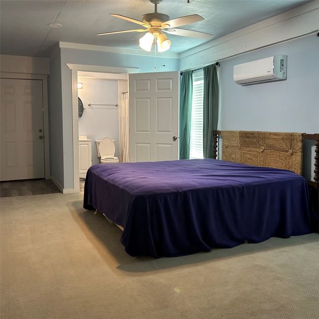 Unfurnished bedroom featuring light colored carpet, a textured ceiling, wooden walls, visible vents, and a ceiling fan | Image 16