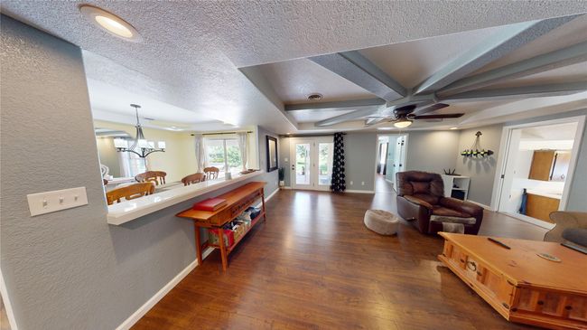 Living room with dark wood-type flooring, a textured wall, a textured ceiling, coffered ceiling, and beamed ceiling | Image 7