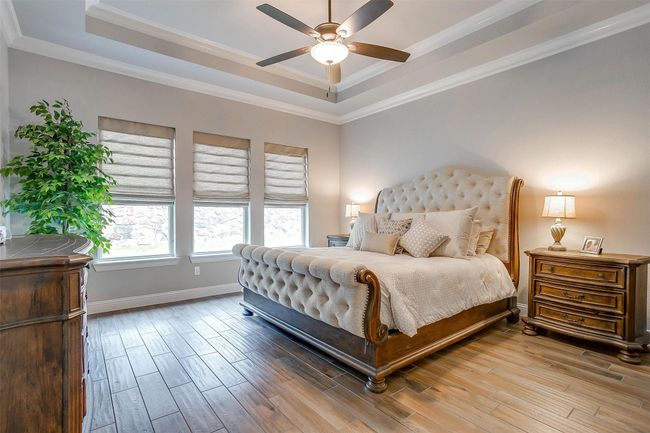 Bedroom featuring a raised ceiling, wood finished floors, ornamental molding, and ceiling fan | Image 28