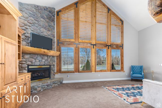 Unfurnished living room with carpet, lofted ceiling, baseboards, and a fireplace | Image 8