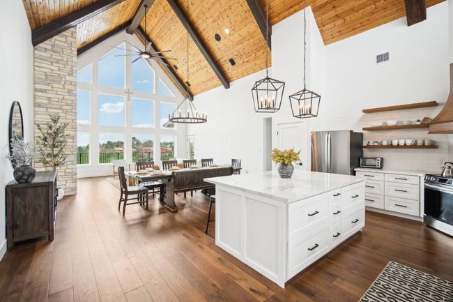 Kitchen with stainless steel appliances, a chandelier, high vaulted ceiling, open shelves, and white cabinetry | Image 7