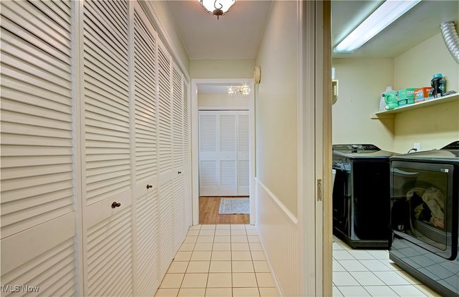 Laundry room with washing machine and dryer, light tile patterned floors, and a chandelier | Image 21