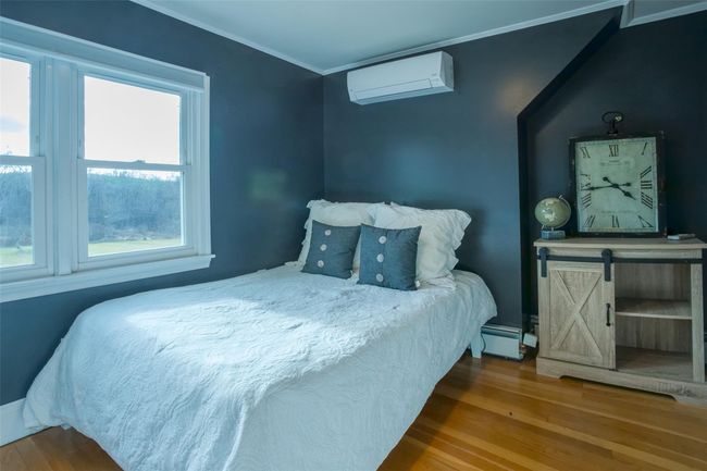 Bedroom with a wall mounted air conditioner, crown molding, hardwood / wood-style flooring, and a baseboard radiator | Image 17