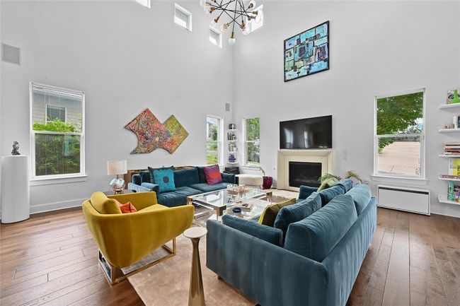 Living room featuring a high ceiling, hardwood / wood-style floors, a chandelier, a fireplace, and radiator | Image 4