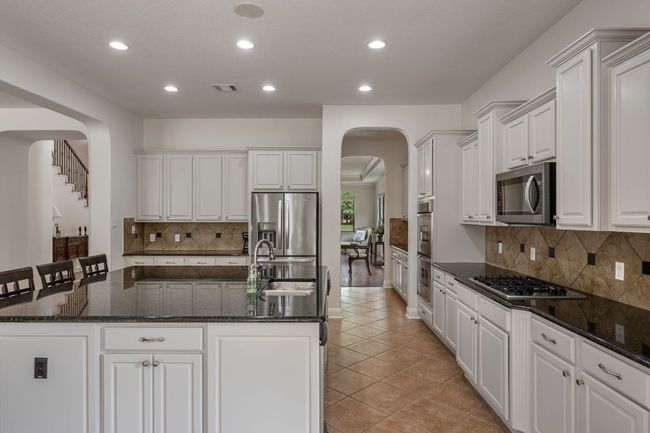 Kitchen with recessed lighting, a sink, stainless steel appliances, a center island with sink, and arched walkways | Image 11