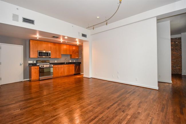Alternate angle showcases the kitchen's stylish design and connection to the living area. Enjoy modern finishes, generous counter space, and a breakfast bar that opens to a sunlit living room with skyline views. | Image 16