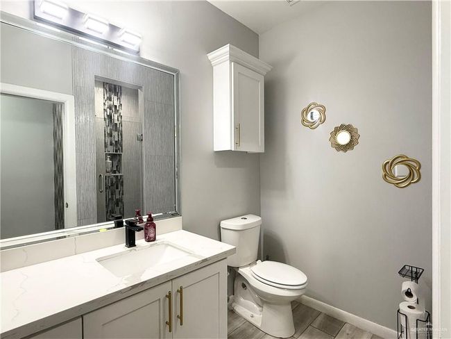 Full bath with wood finished floors, vanity, toilet, tiled shower, and baseboards | Image 12