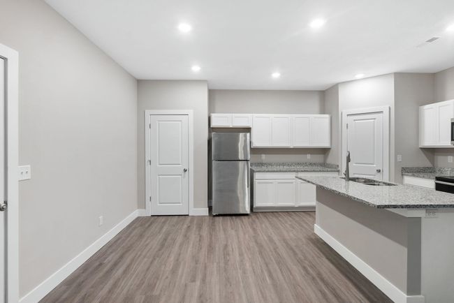 Kitchen with freestanding refrigerator, a sink, light wood-type flooring, light stone counters, and recessed lighting | Image 11