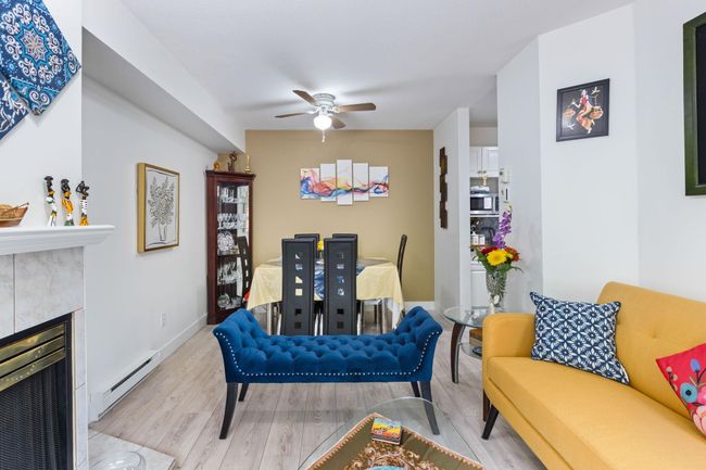 Living room featuring a baseboard radiator, wood finished floors, a ceiling fan, and a tiled fireplace | Image 7