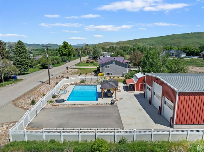 View of swimming pool with a mountain view, a fenced backyard, and an outdoor structure | Image 36