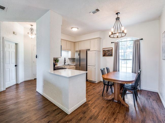 Kitchen with a chandelier, dark wood-style flooring, freestanding refrigerator, backsplash, and a textured ceiling | Image 7