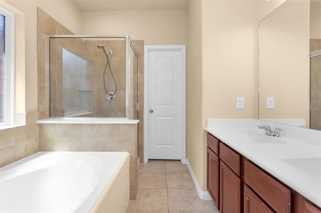 The primary ensuite bathroom offers tile flooring, a dual-sink vanity with ample lower cabinet storage, and a large mirror. | Image 15
