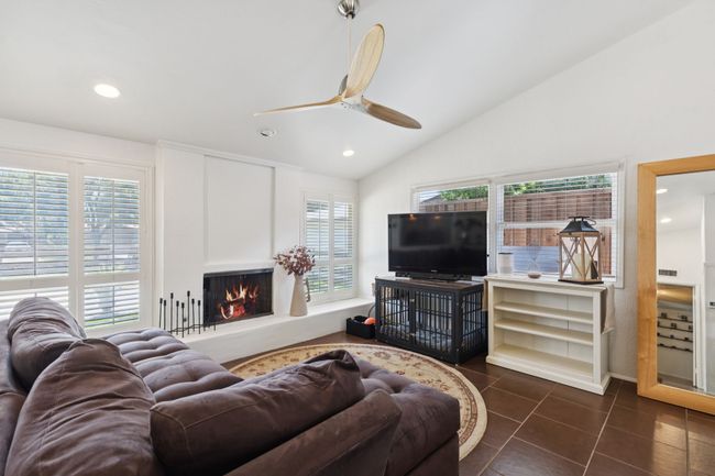 Living room with vaulted ceiling, a ceiling fan, a lit fireplace, recessed lighting, and tile patterned floors | Image 5