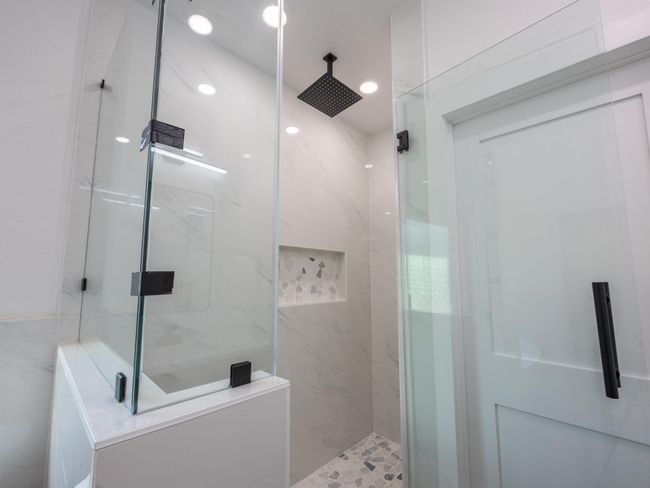 Step into this elegant walk-in shower featuring full-height tile surround, a niche for essentials, and a matte black rain showerhead for that spa-day feel at home. | Image 26