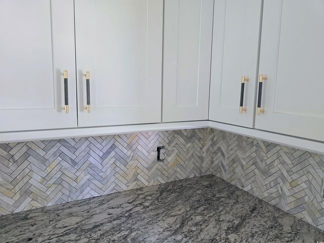 Kitchen view of white cabinets and light stone countertops | Image 13