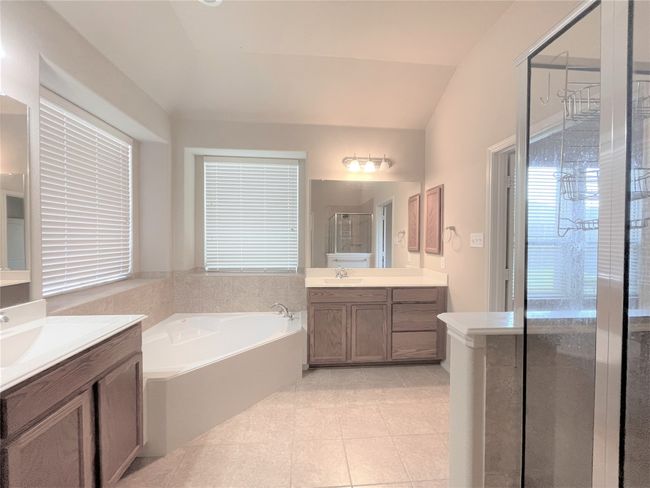 Bathroom featuring two vanities, a stall shower, a garden tub, tile patterned flooring, and lofted ceiling | Image 11