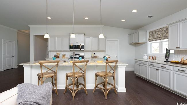 Kitchen featuring appliances with stainless steel finishes, tasteful backsplash, a breakfast bar area, and an island with sink | Image 8