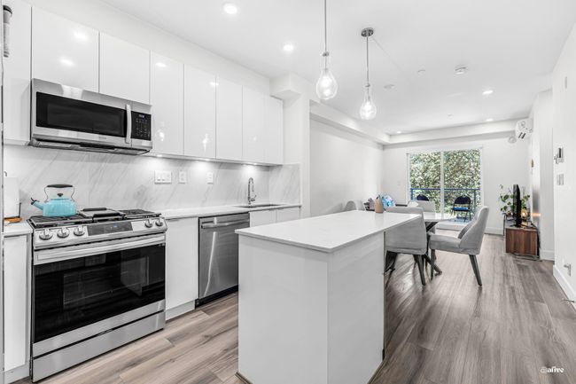 Kitchen with stainless steel appliances, modern cabinets, light wood-style flooring, backsplash, and recessed lighting | Image 4